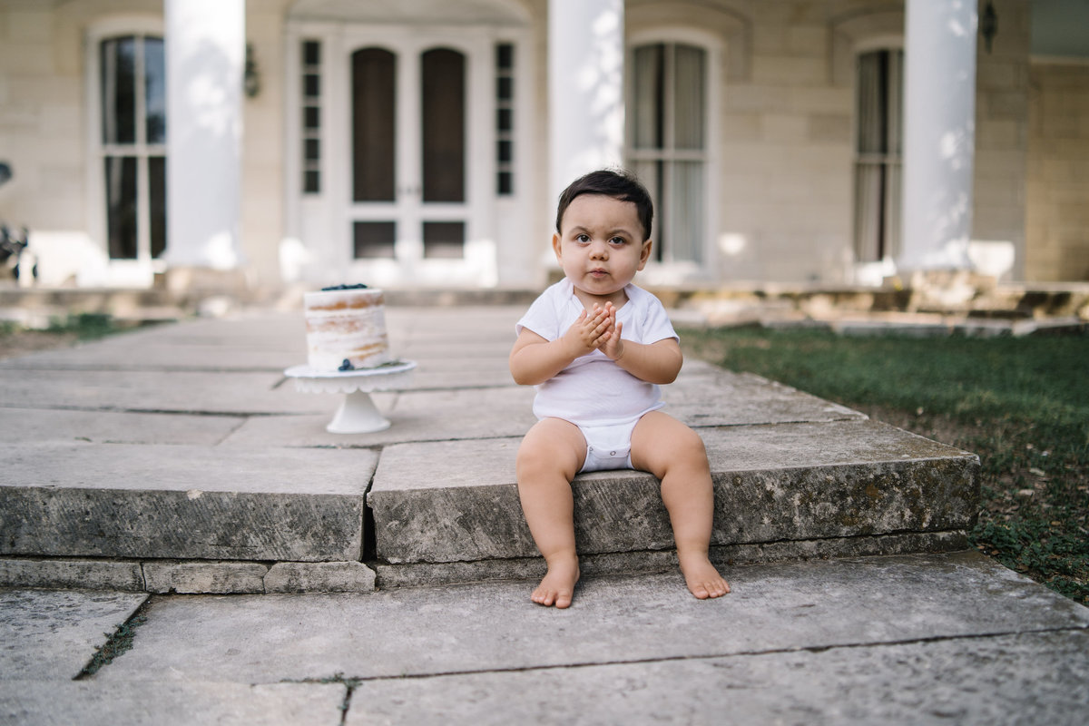 Cake smash photography session of baby sitting on the steps of Denman Estate Park in San Antonio