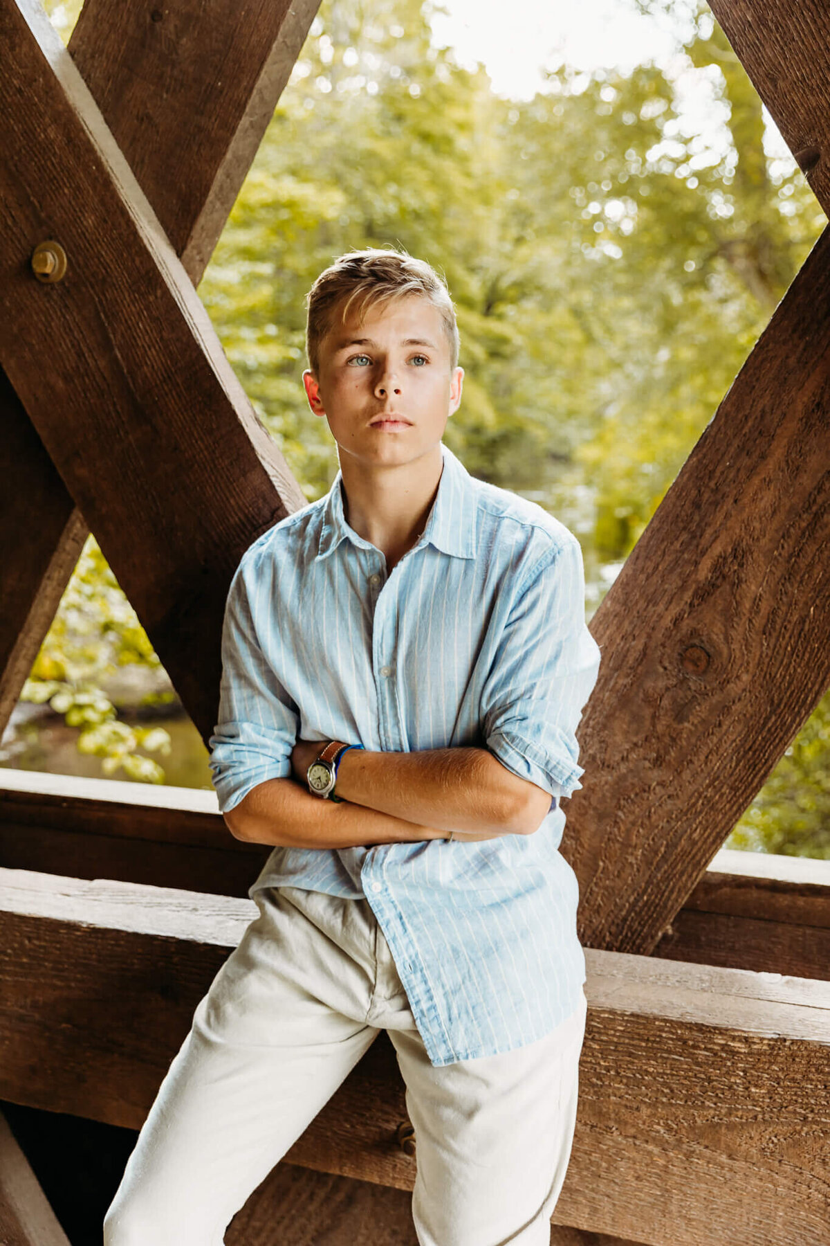 high school senior sitting in a covered bridge and looking into the distance
