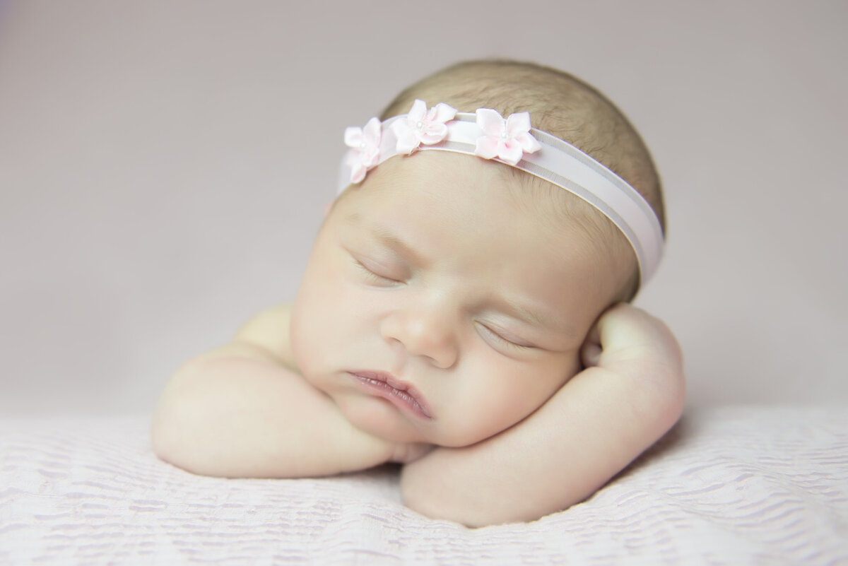 Newborn baby girl in headband on pink in Kennebunkport Maine