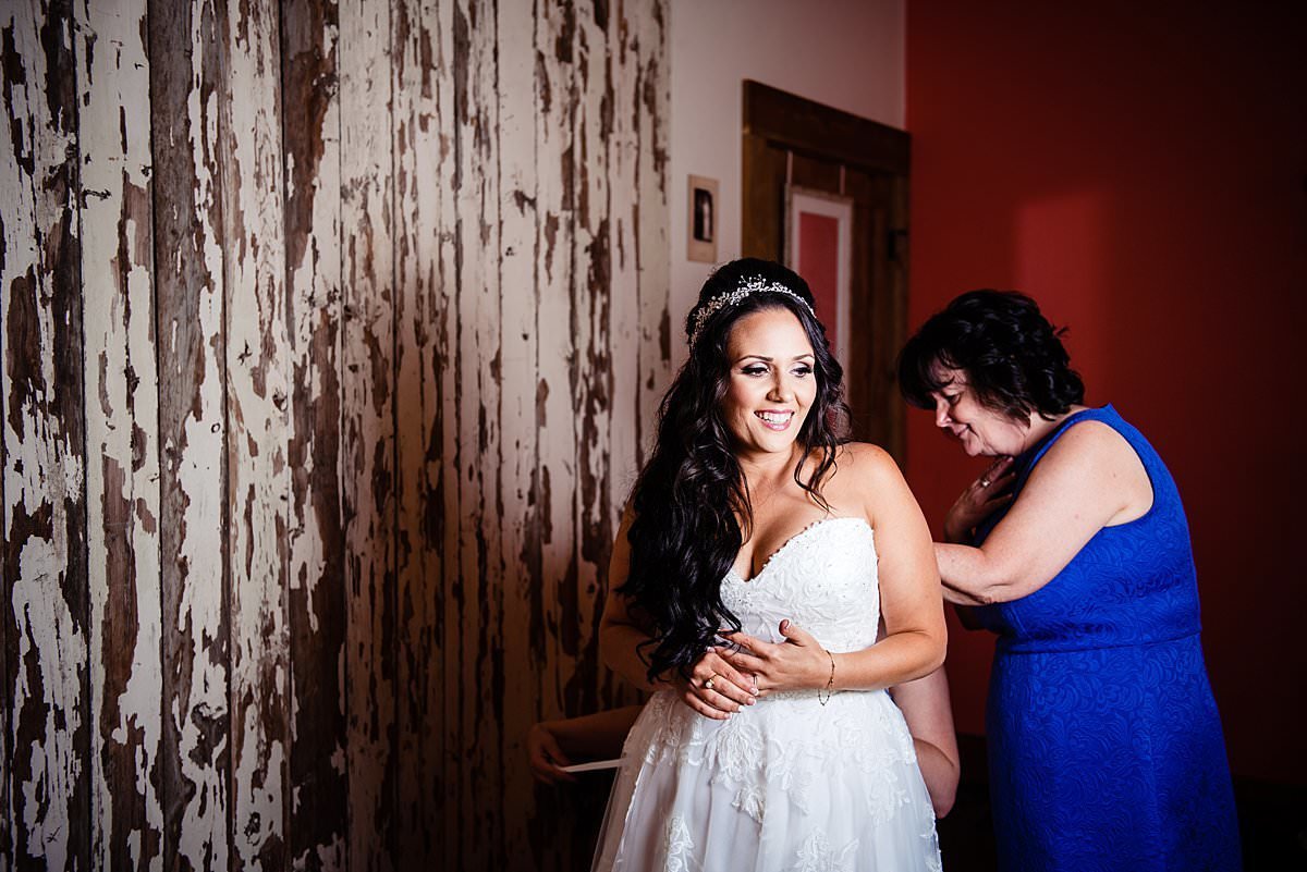 Mothe of the bride standing in Headwaters Ranch bride suite zipping her daughter into her wedding dress