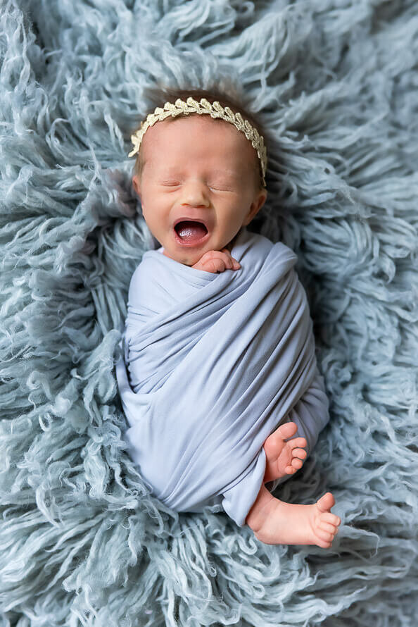 Newborn baby yawns during her newborn photos.