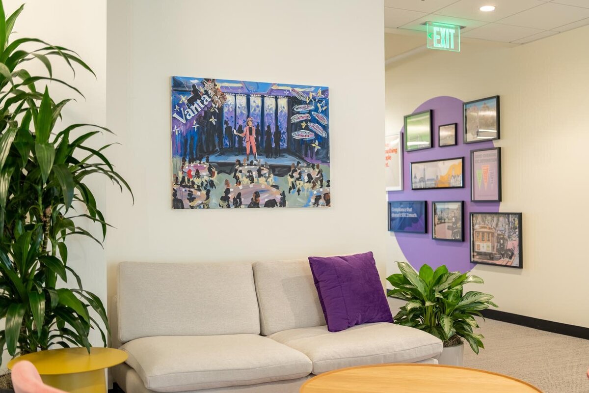 Lounge seating area with light sofa, purple pillow, large themed painting, and gallery wall in the background.