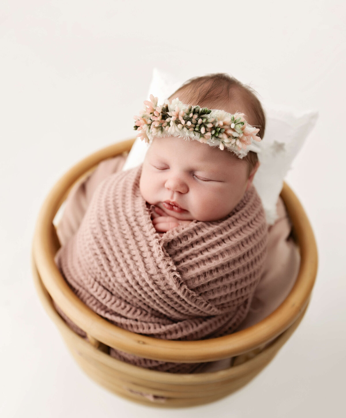 Newborn photo of a baby in a basket wrapped in pink in an Erie Pa photography studio