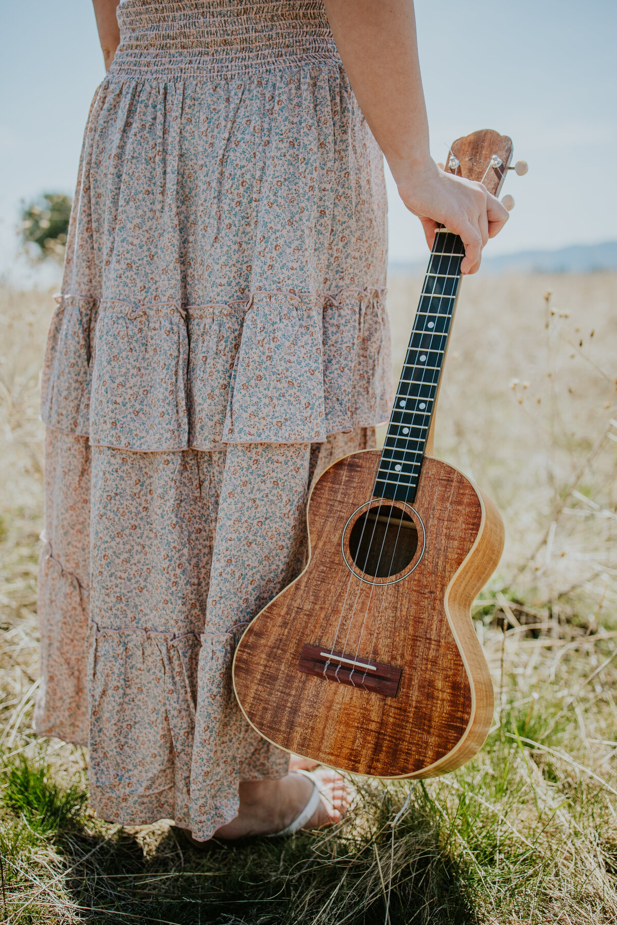 Shot of girl wearing skirt from waist down holding ukulele.