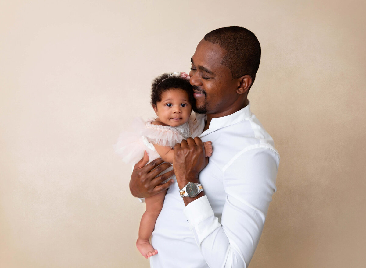 Father holding and smiling at her baby girl during milestone photos done by Professional  NYC baby photographer 