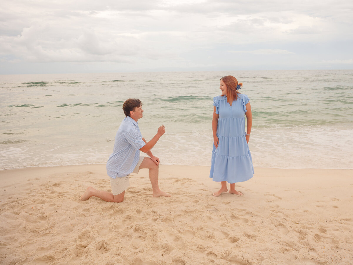 Girl in dress being proposed on the beach 