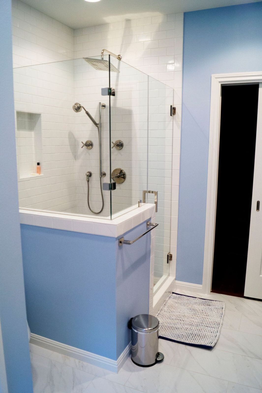 dusty blue bathroom with walk in shower and white marble tiles.