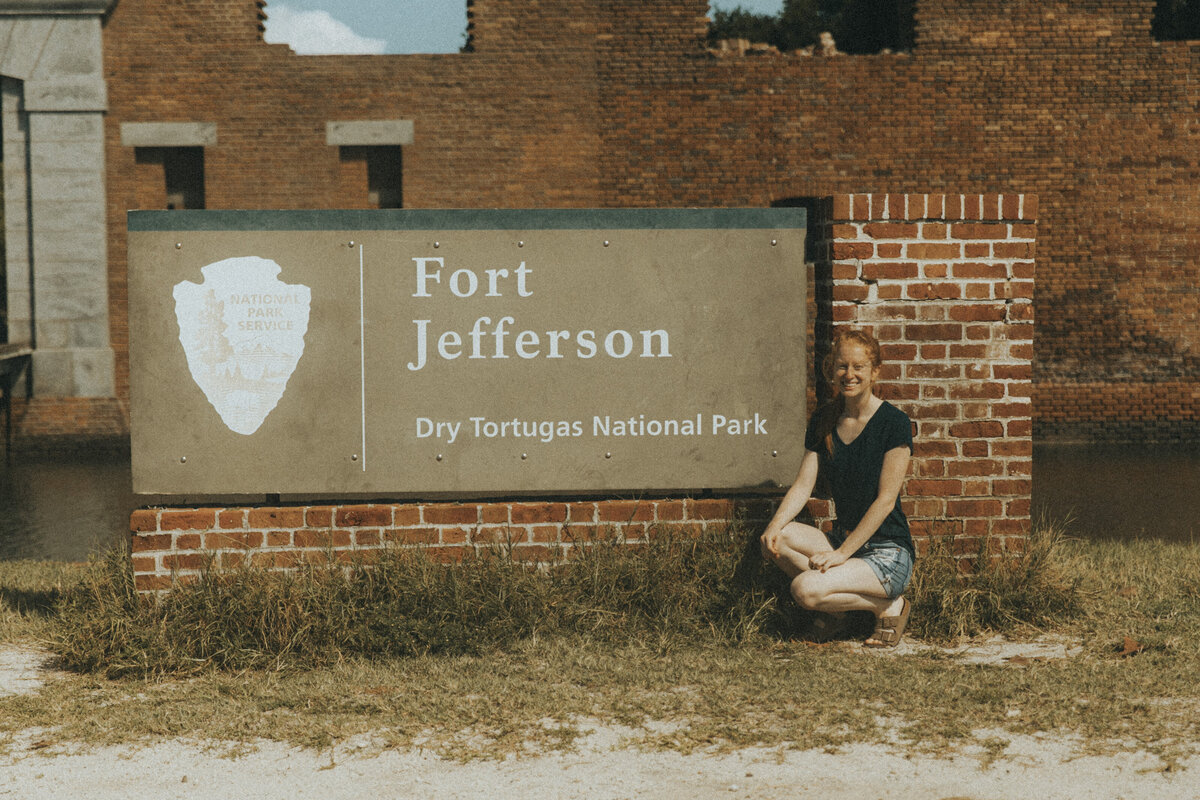 women sitting in front of dry tortugas national park sign