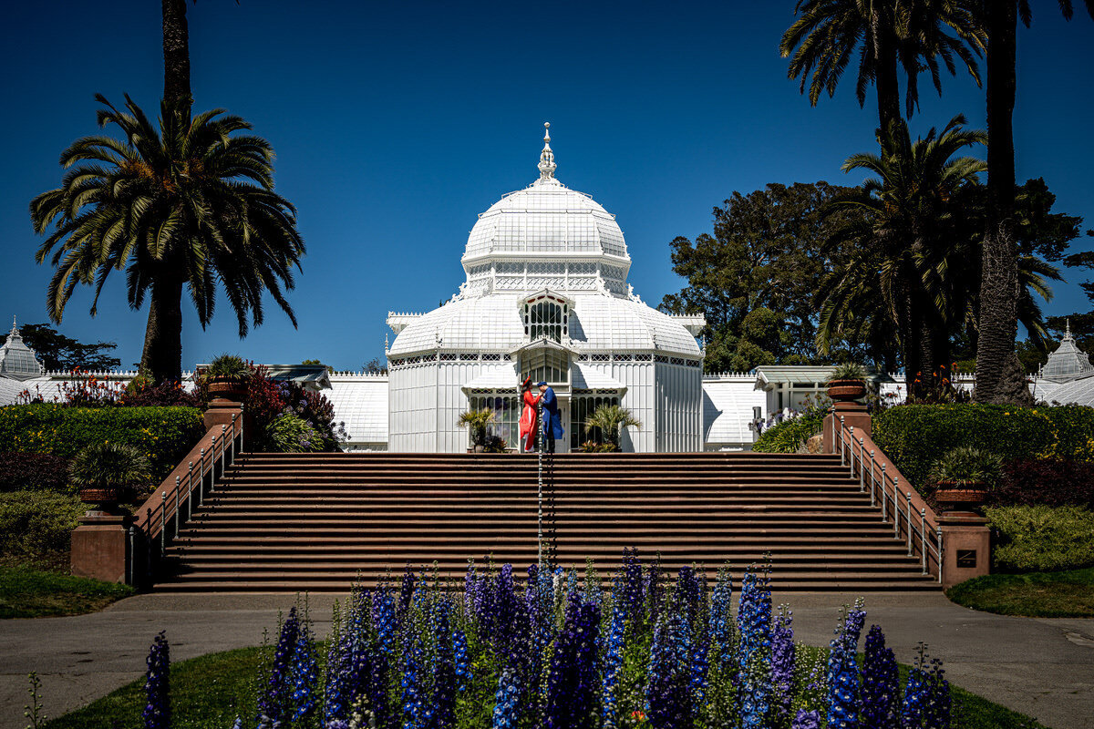 This beautiful engagement session took place at the iconic Conservatory of Flowers in San Francisco. The couple posed on the grand steps with the stunning white architecture of the conservatory and the vibrant, colorful gardens as a backdrop. The bright blue sky and tall palm trees added to the elegance of the shoot, making this a perfect blend of nature and history. The location provided an ideal setting for capturing candid moments between the couple, surrounded by the beauty of Golden Gate Park.