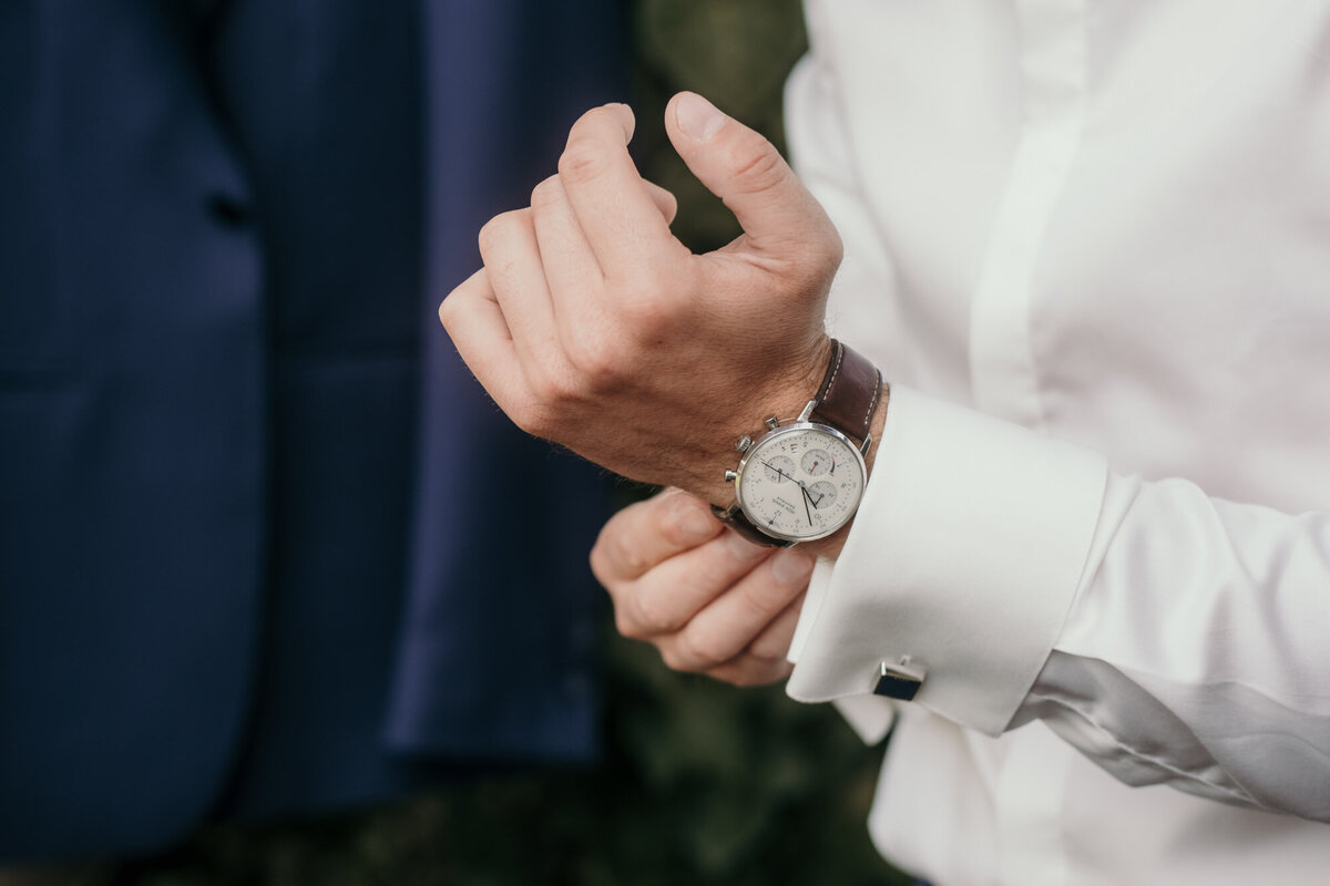 Diese Nahaufnahme zeigt, wie sich der Bräutigam seine Uhr anzieht.