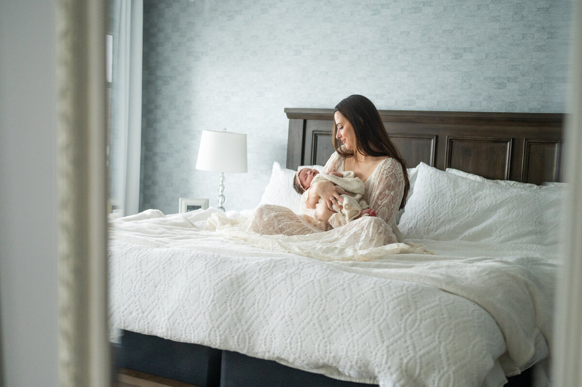 mother holding her newborn baby on her bed