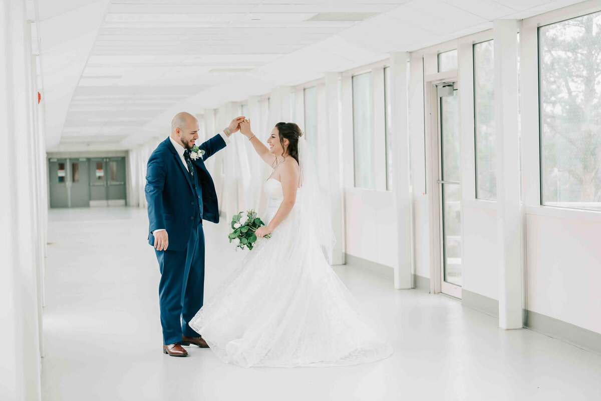 Groom raises brides hand and spins her slowly/ 