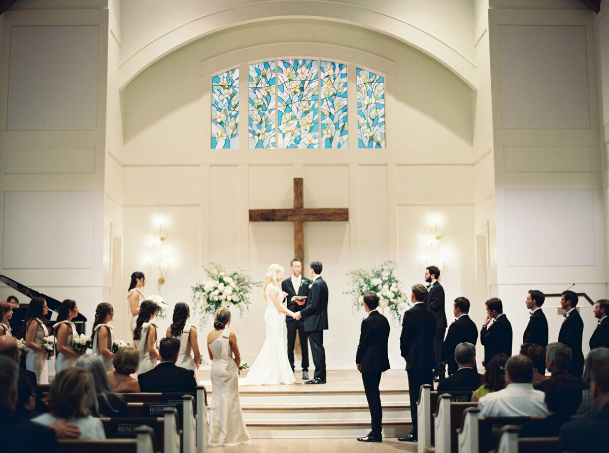 A heartfelt moment as the bride and groom stand together at the altar, exchanging vows and promises, timelessly captured on film by Morgan Alysse, Louisiana film photographer.