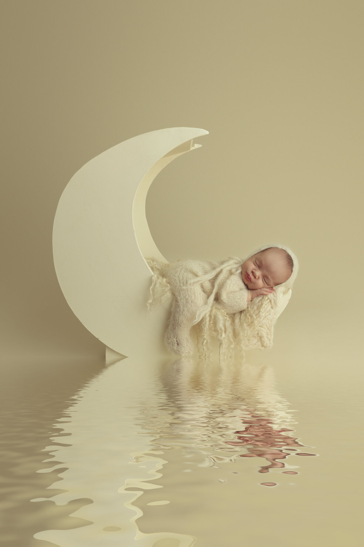 A newborn baby sleeps in froggy pose in a yellow onesie in a moon shaped bed over waterNJ Newborn Photography