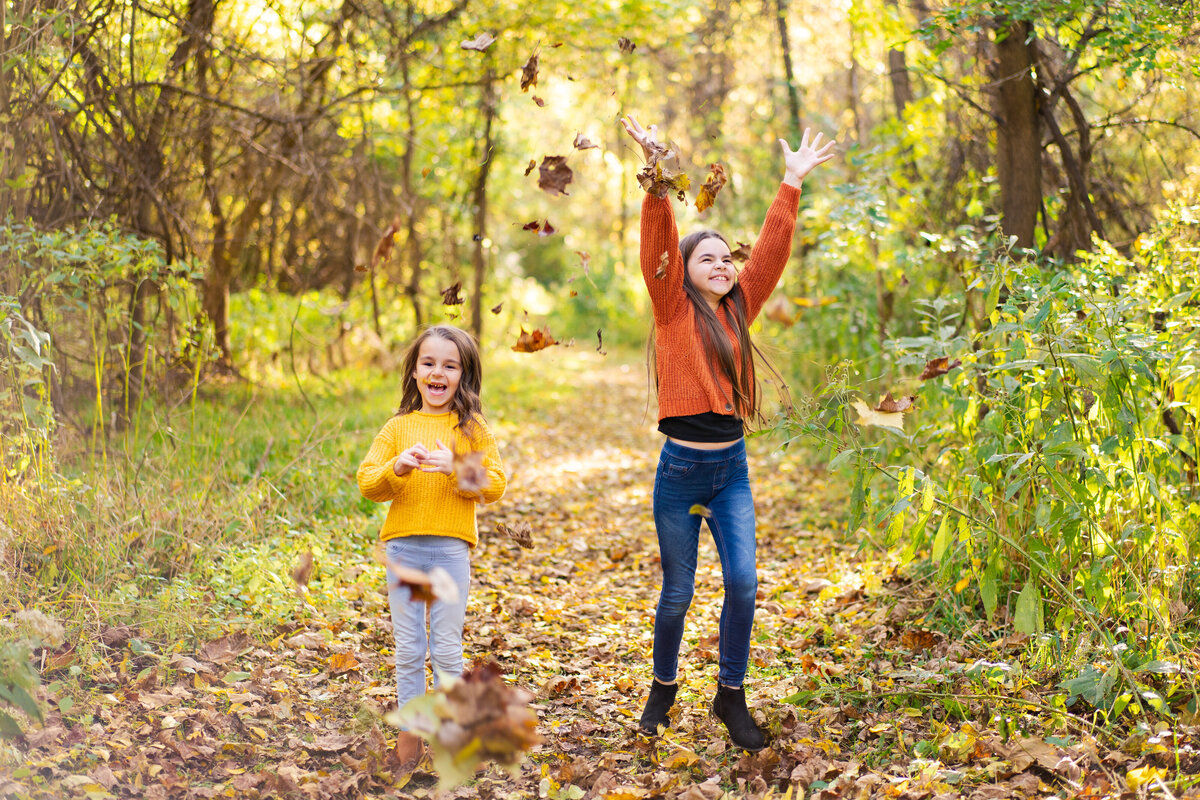 Two sisters laughing and throwing leaves into the air in Canal Winchester, Ohio.