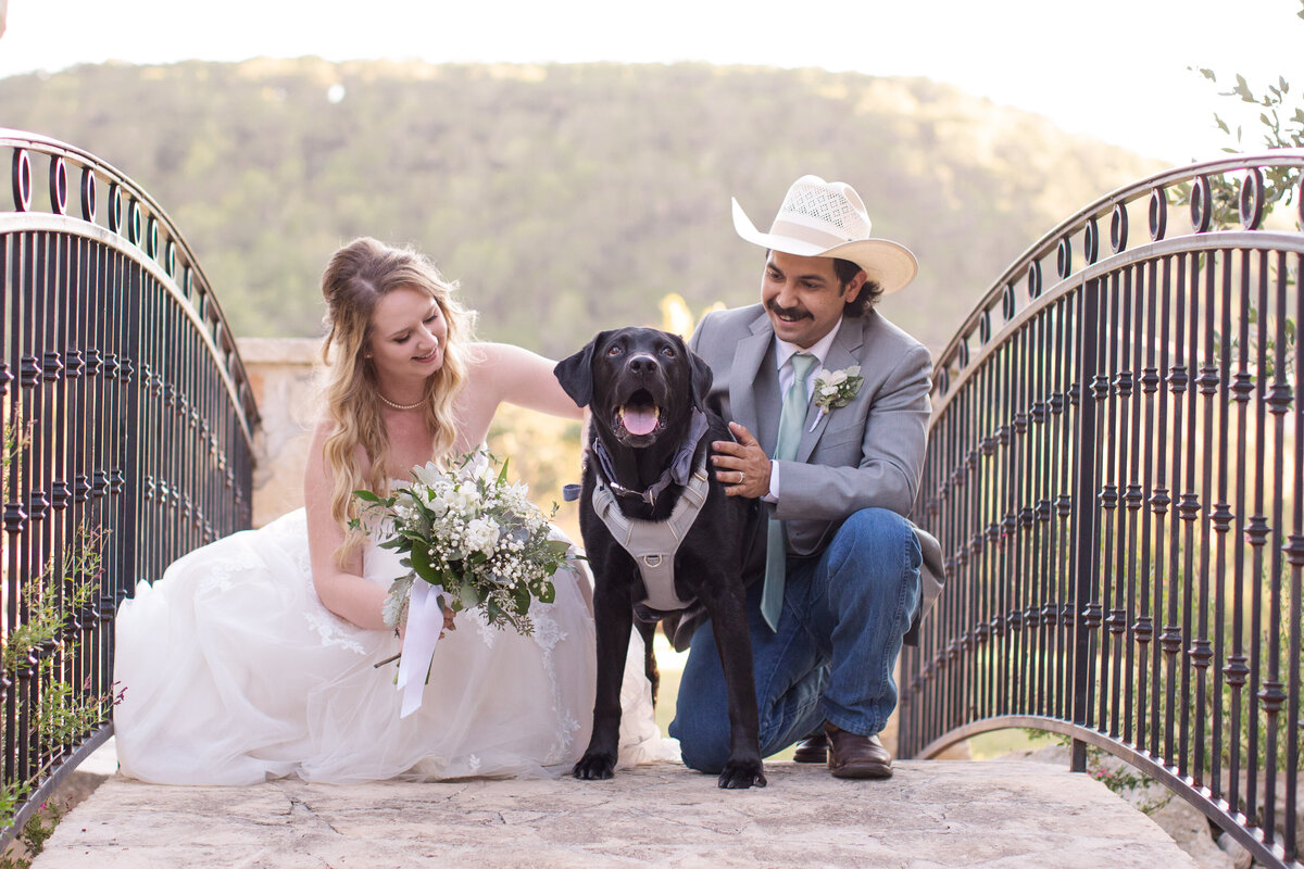 bride and groom kneel down by black lab dog at Boerne wedding