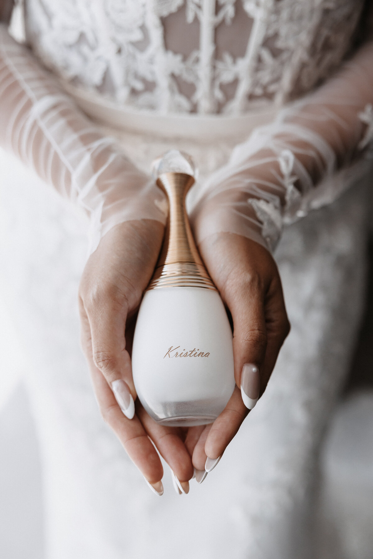 Bride with french nail tips and lace wedding dress holding perfume that says Kristina