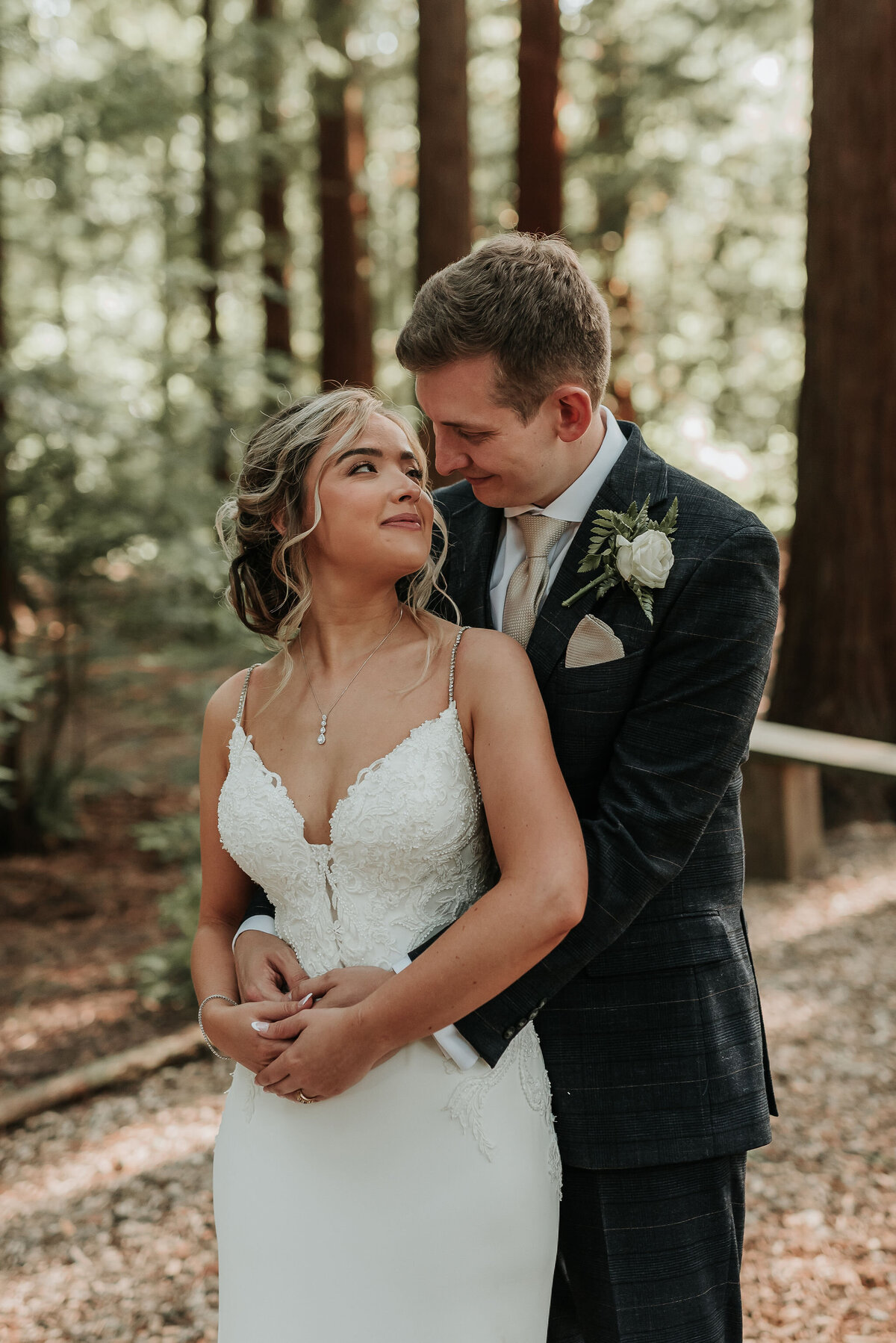 Groom embraces his Bride gently at their outdoor woodland wedding at Two Woods Estate
