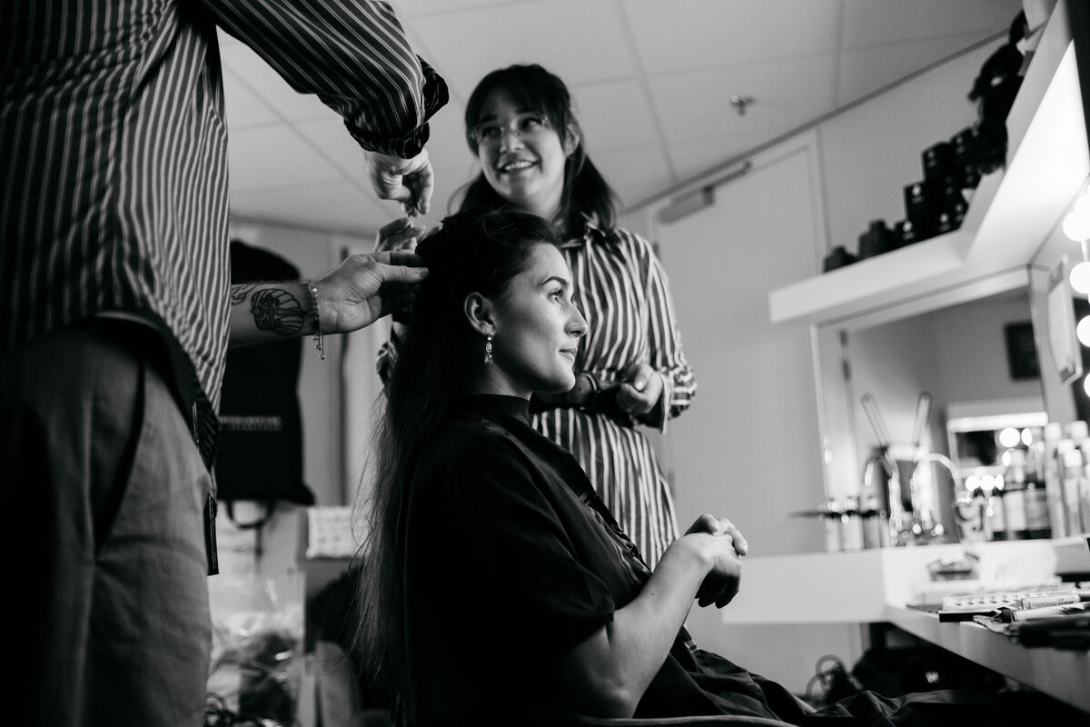 Zwart wit portret van actrice in haar en make-up stoel die in de spiegel kijkt.