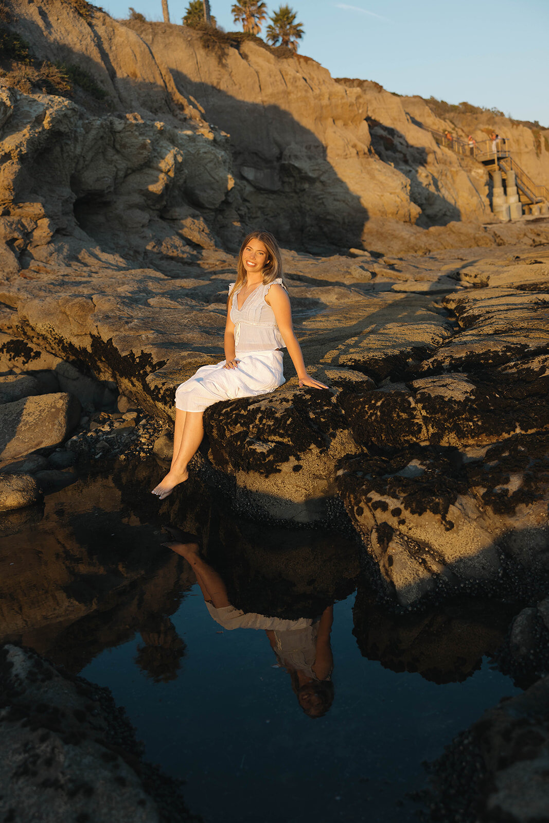 Senior girl sitting on golden cliffs at sunset