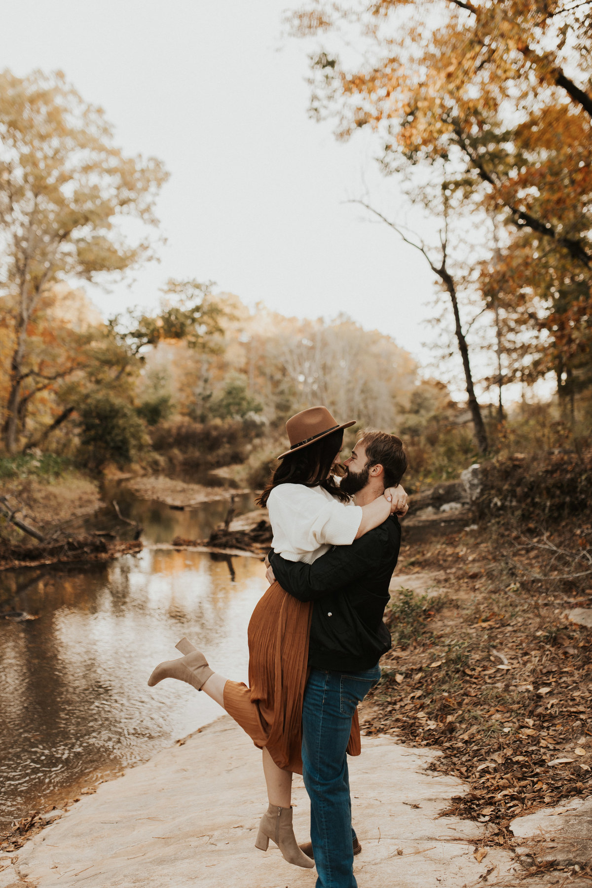 A couple standing and kissing in front of a creek