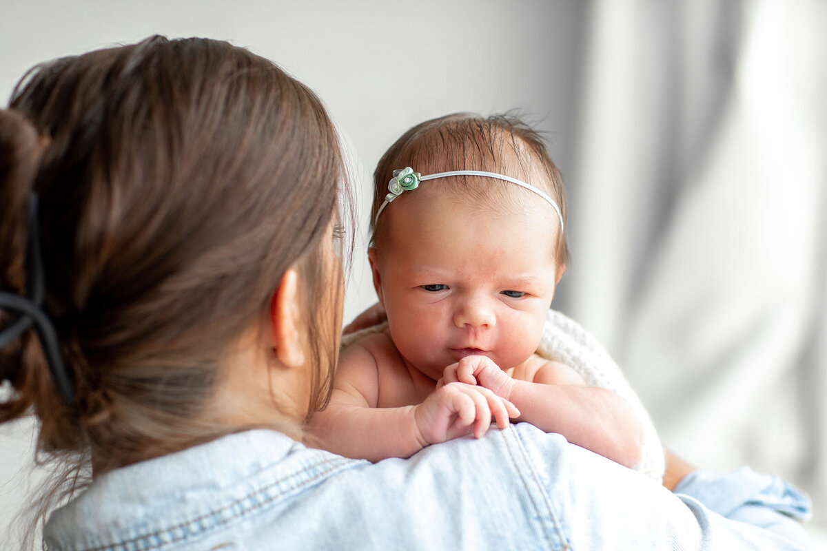 a mother holds a very awake newborn on her shoulder
