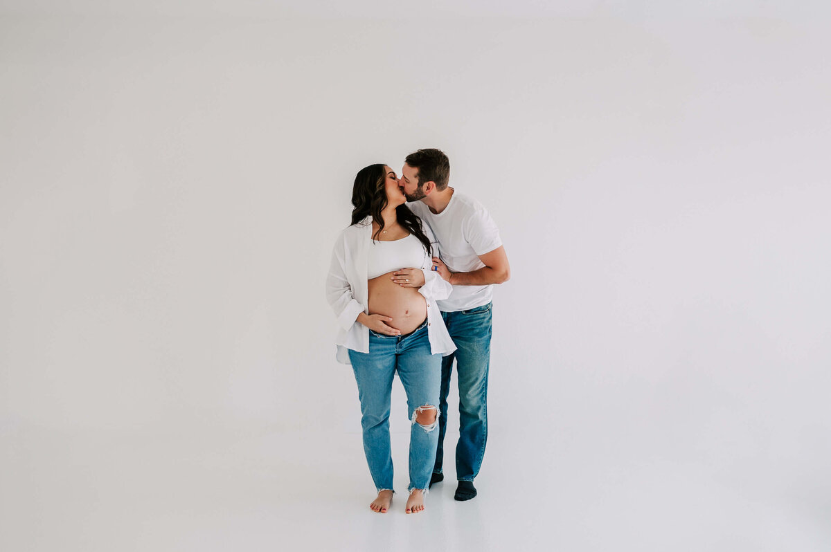 Branson matenrity photographer captures prengnat couple in jeans kissing in studio
