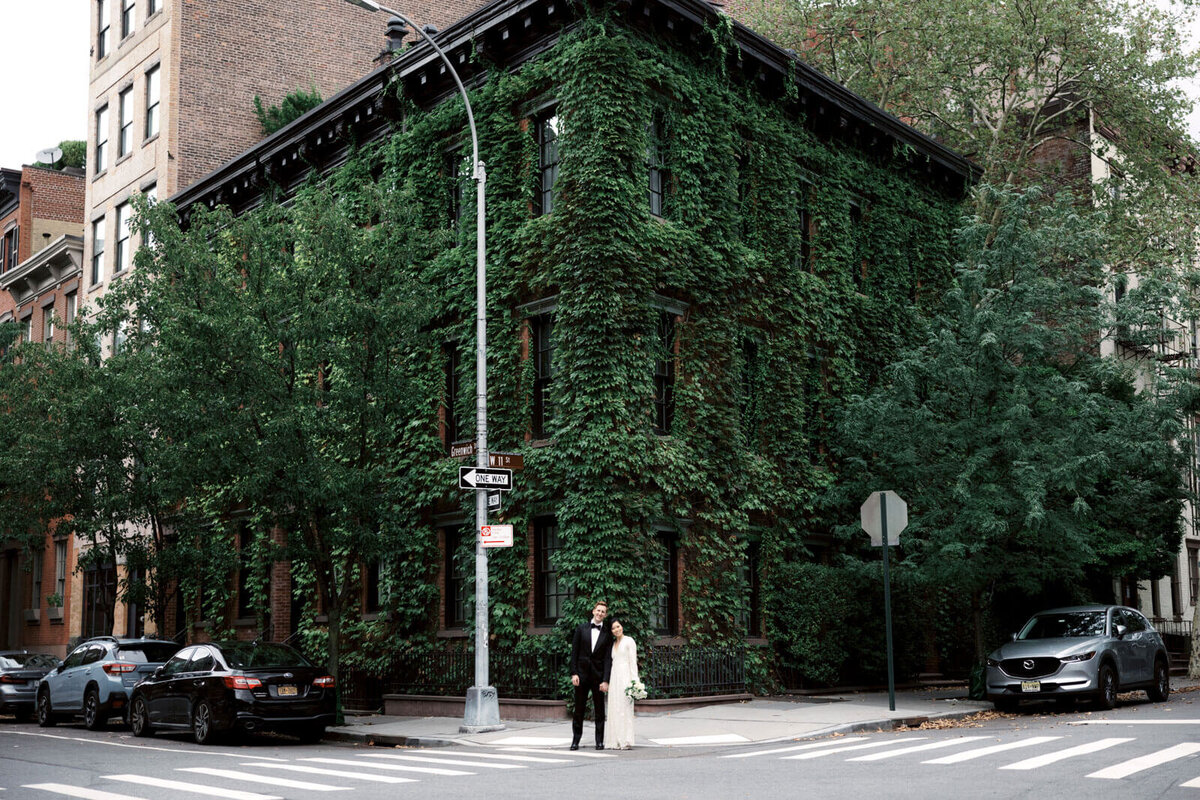The bride and the groom are standing in the corner of an ivy-covered building in West Village, NYC. Image by Jenny Fu Studio