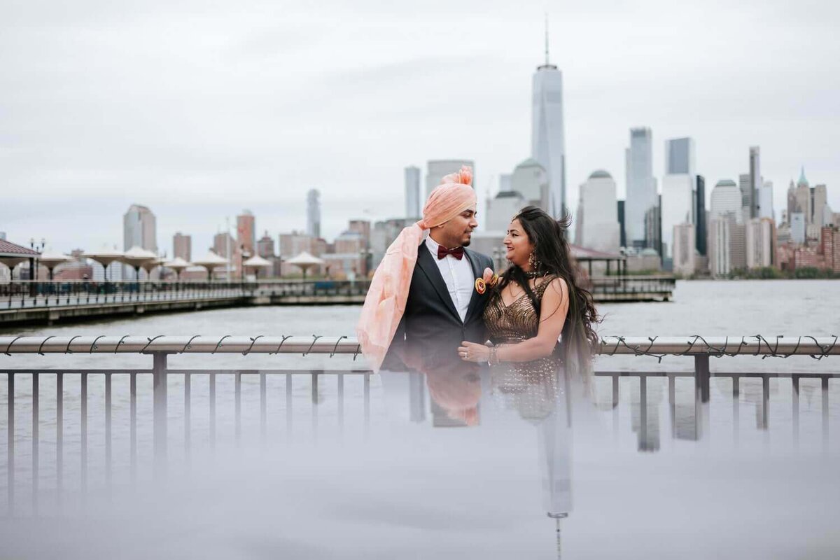 Couple glare at each other and hold hands in front of New York City skyline.