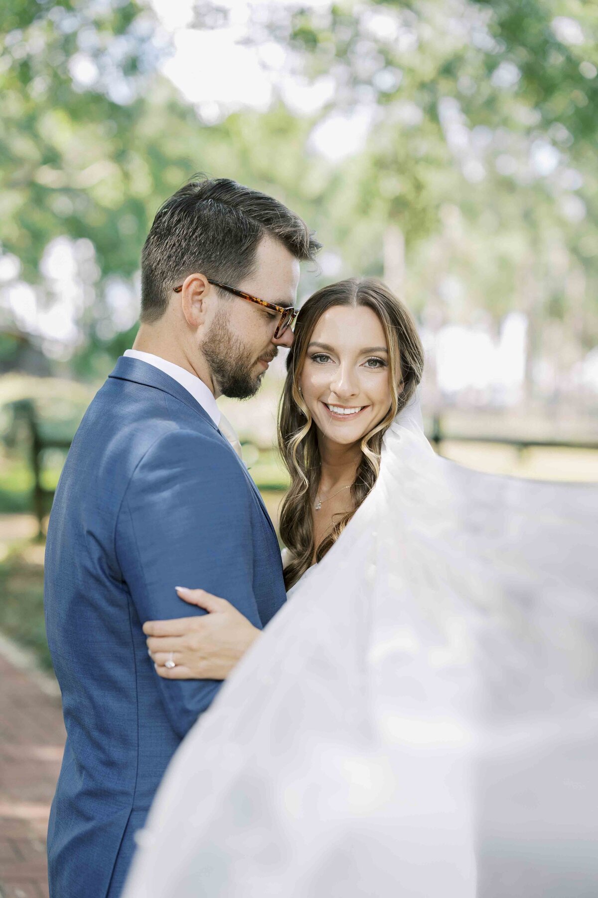 a bride smiling at the camera while embracing her husband