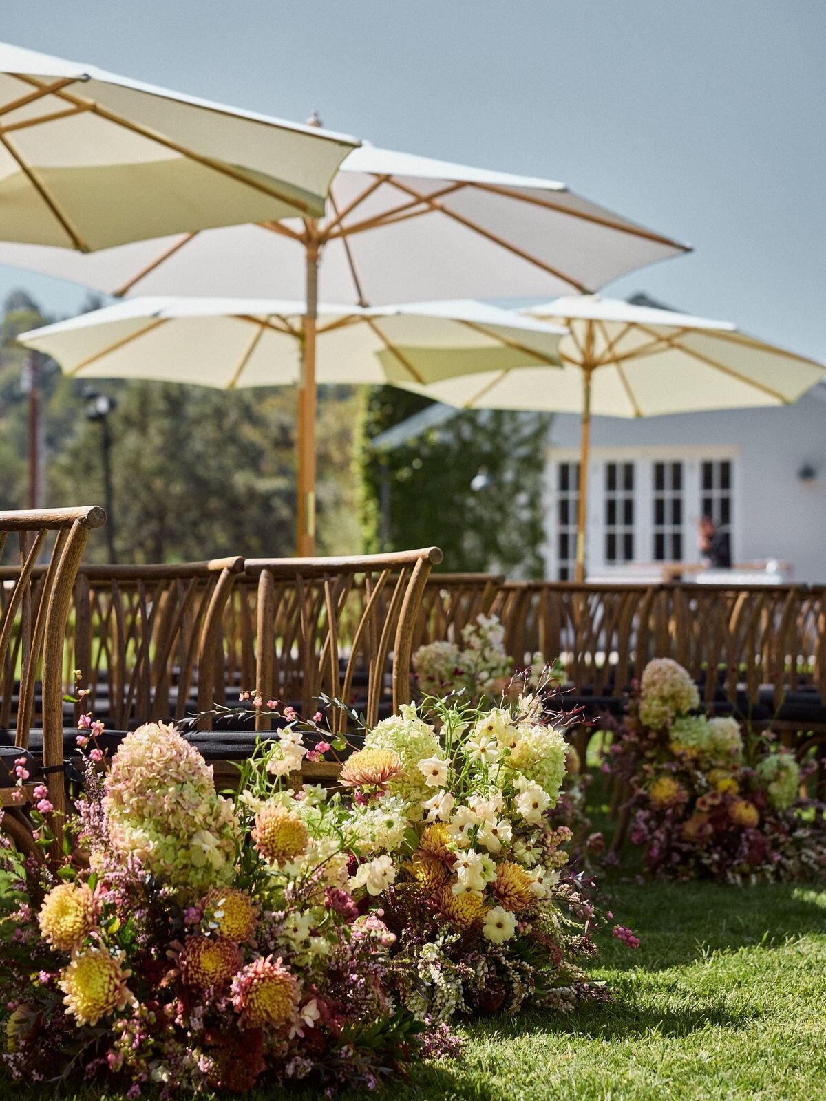 Lawn wedding reception with umbrellas and floral clusters, design inspiration for Wrightsville Manor outdoor events