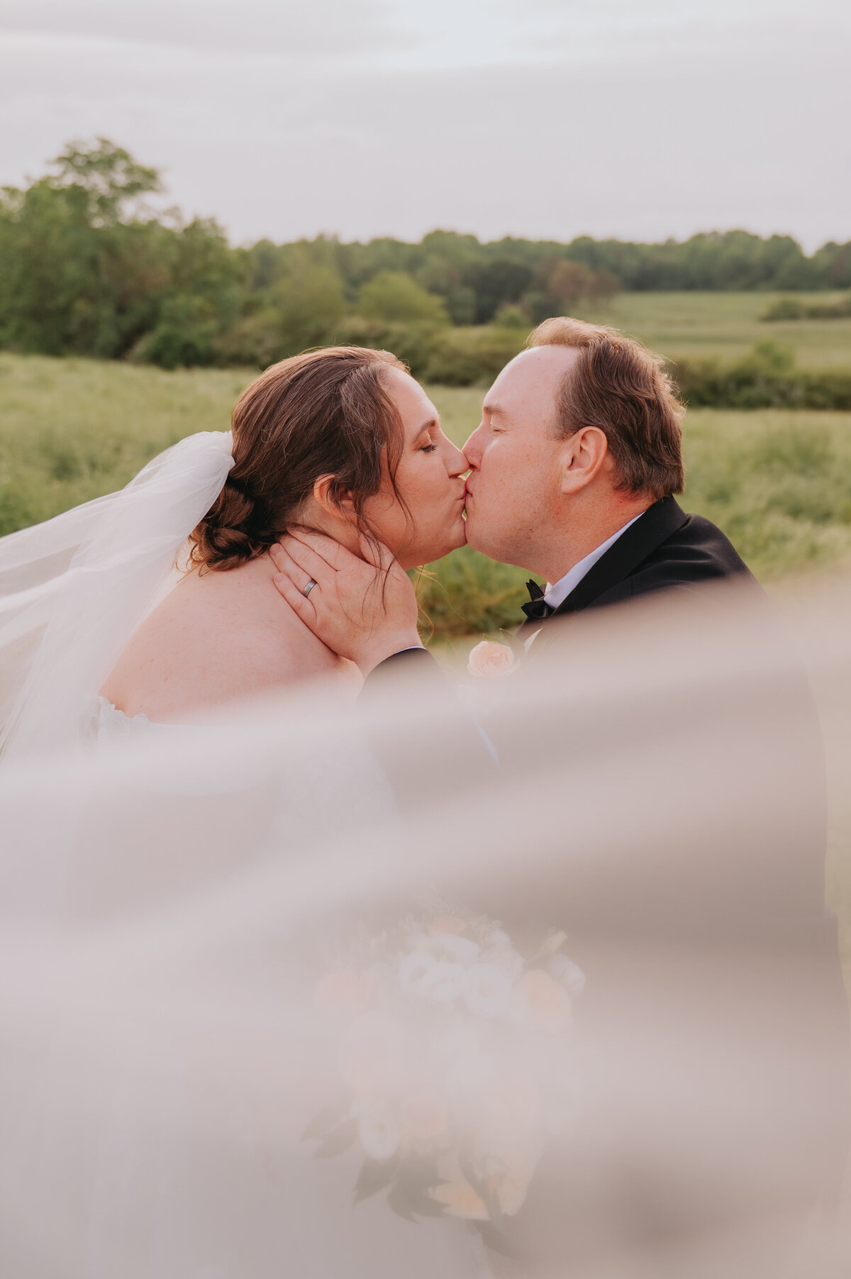 A couple leans in for a kiss outdoors