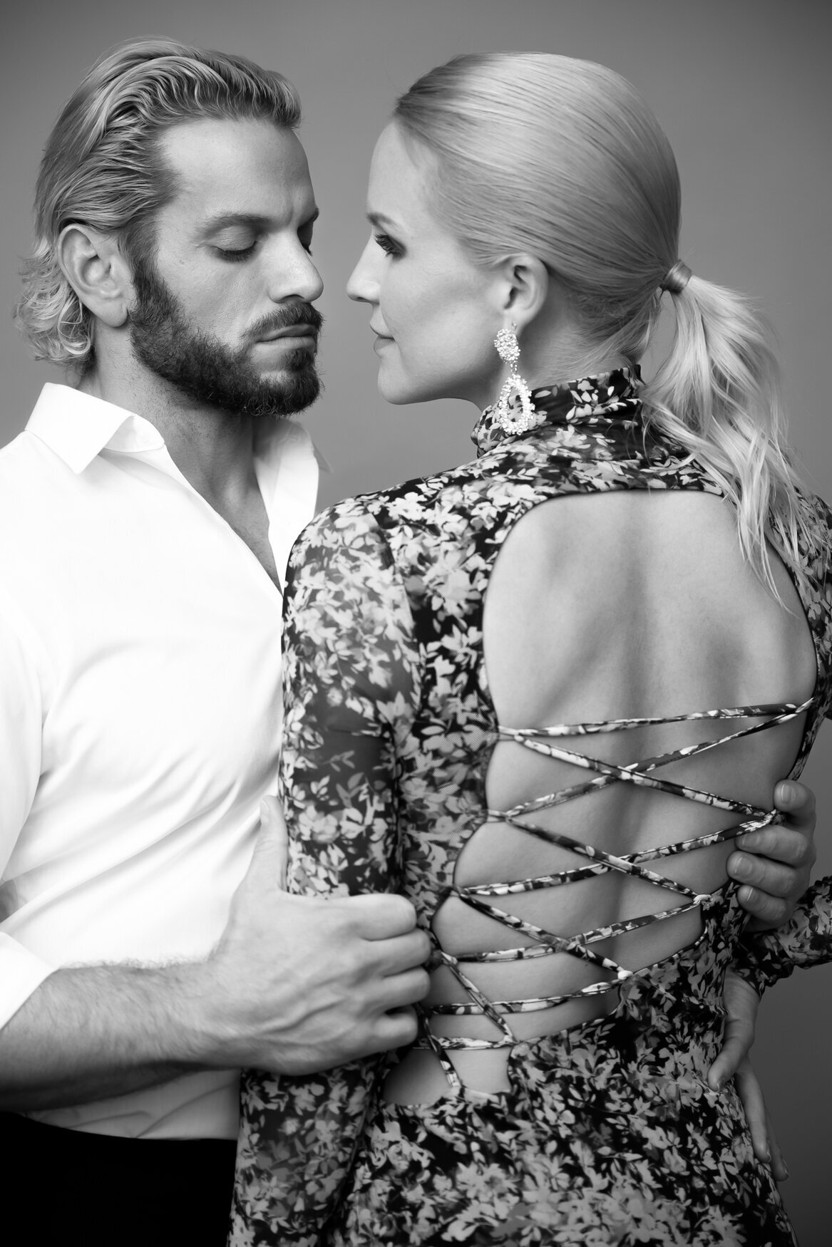 photo of a couples while the man is grabbing the woman arm looking at her lips while she is looking at his eyes