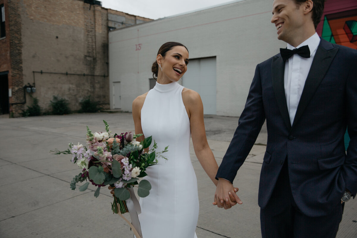 Newlywed couple walking hand in hand in alleyway of downtown Chicago