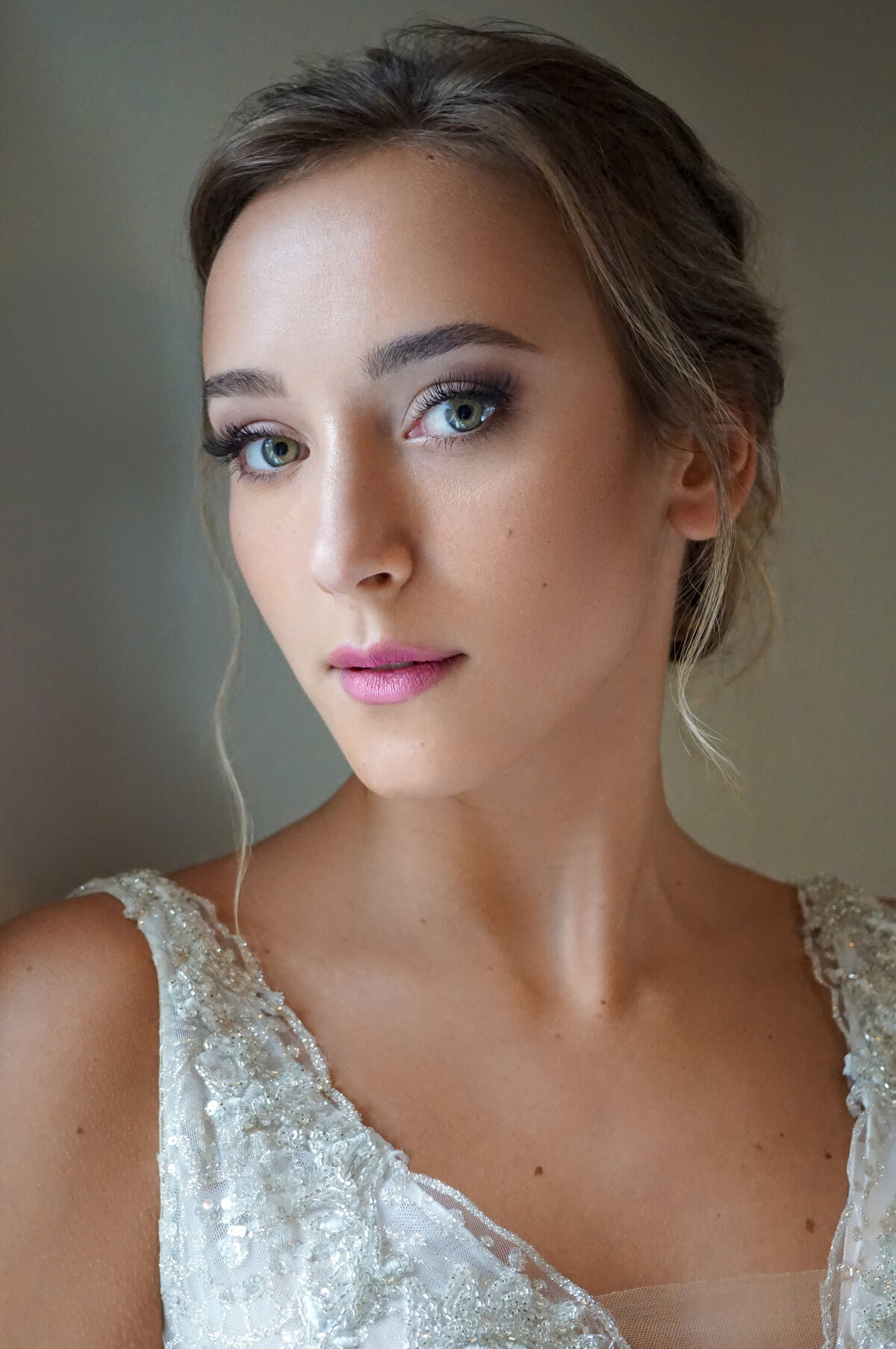 A brunette looks into the camera while wearing pink lips and a soft glam eye makeup.