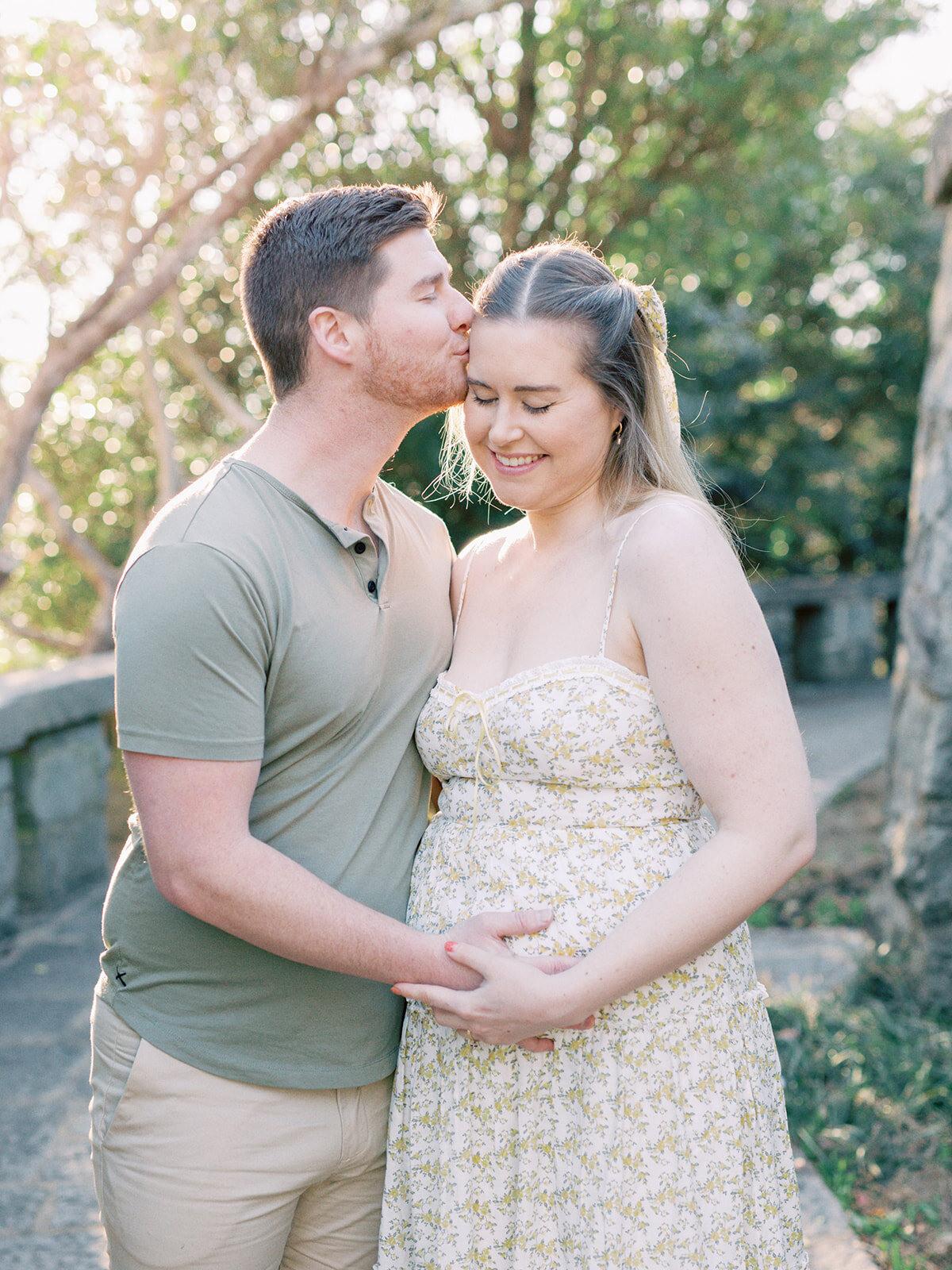 A man kissing a woman's temple while holding the woman's pregnancy bump during a Richmond maternity photography session by Katie Stansfield Photography.