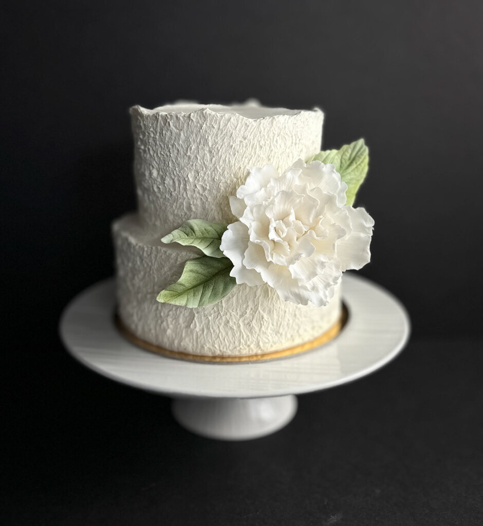 Beautiful professional two-tiered textured white wedding cake, with white sugar florals, created by Chartier YYC, elegant cakes & desserts in Calgary, AB, featured on the Brontë Bride Vendor Guide.