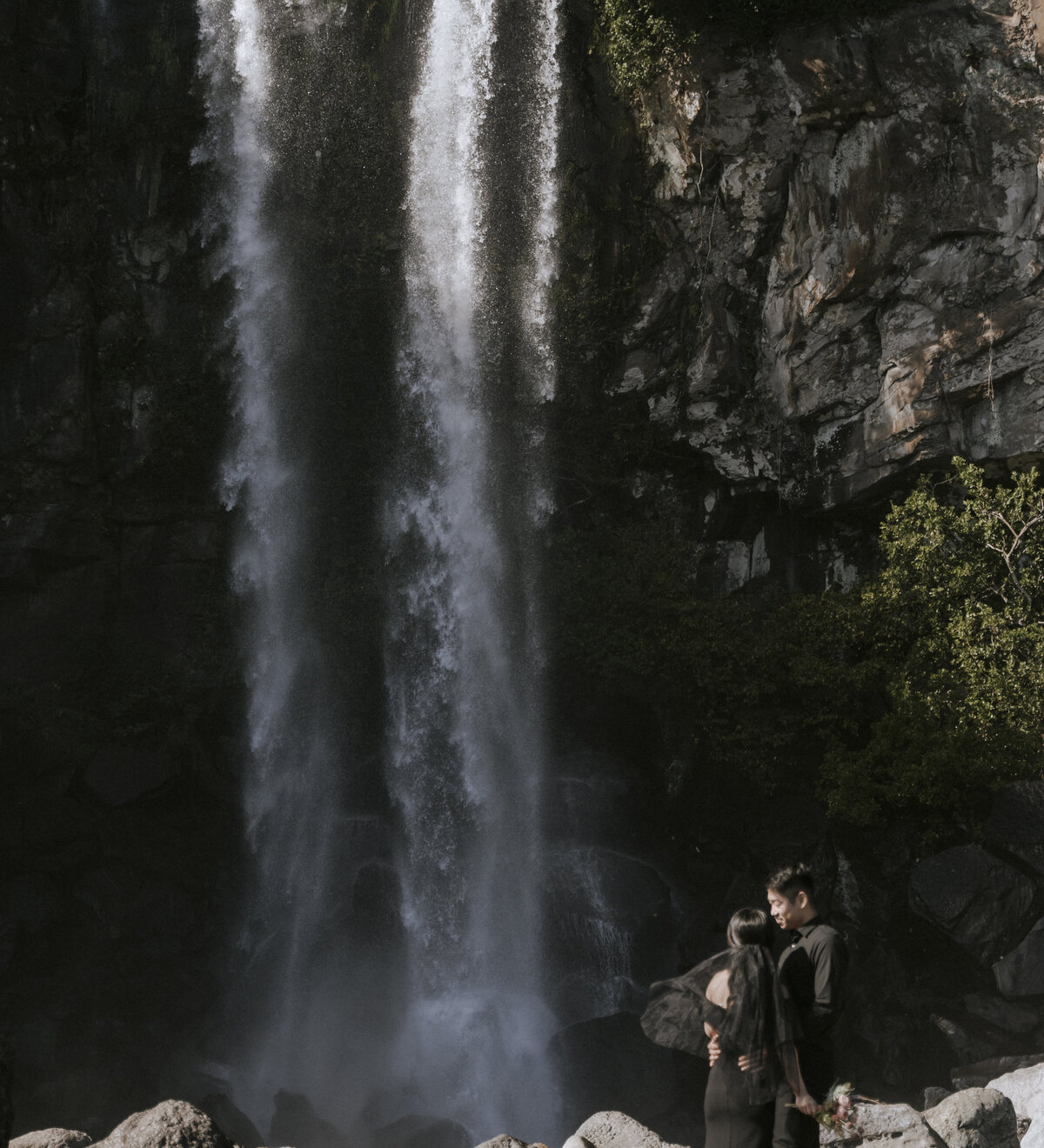 bride and groom in front of Jeongbang waterfall in Jeju during their pre-wedding photoshoot