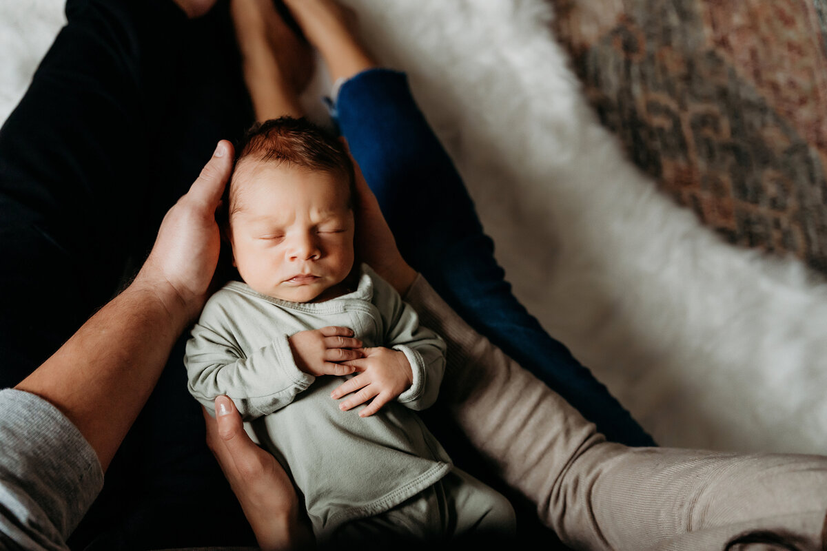 Newborn Photographer, a mother and father's arms holds their new bbay