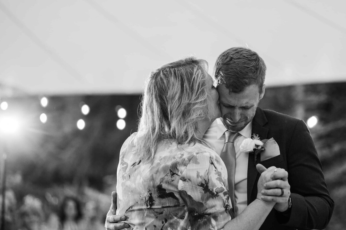 Mother of groom, whispering into his ear during mother son dance at wedding