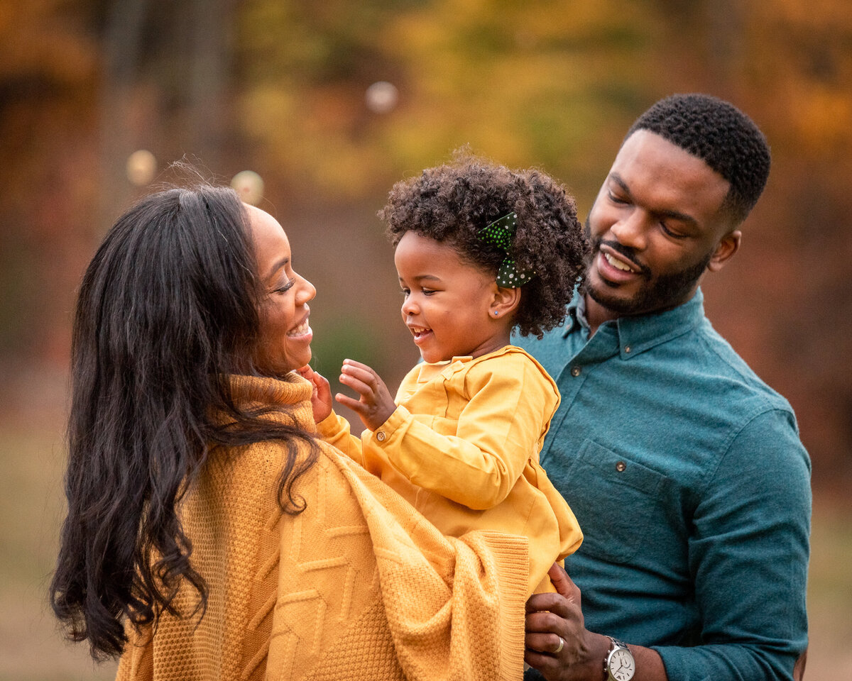 Family enjoying a photography session on a farm near Boston,  holding toddler and embracing