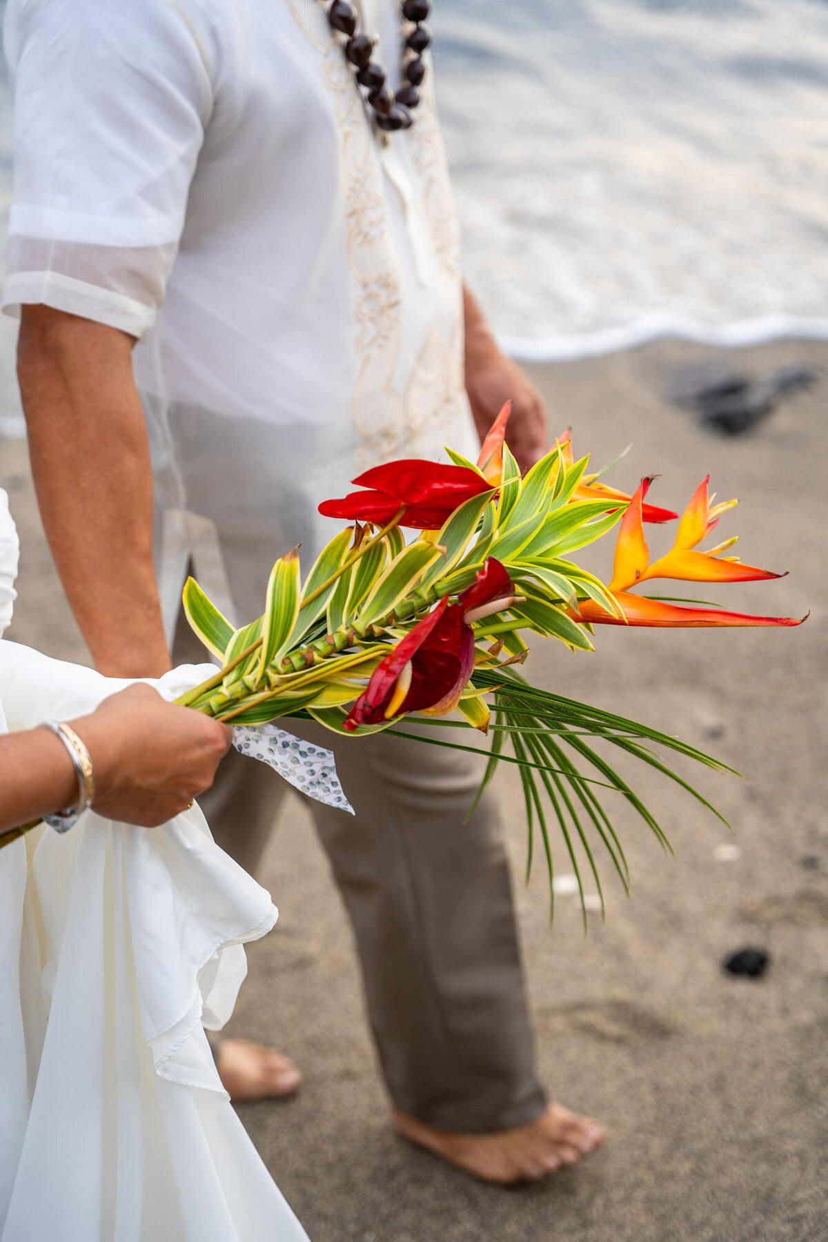 Bride and groom with flower bouquet on the beach, by Big Island photographers