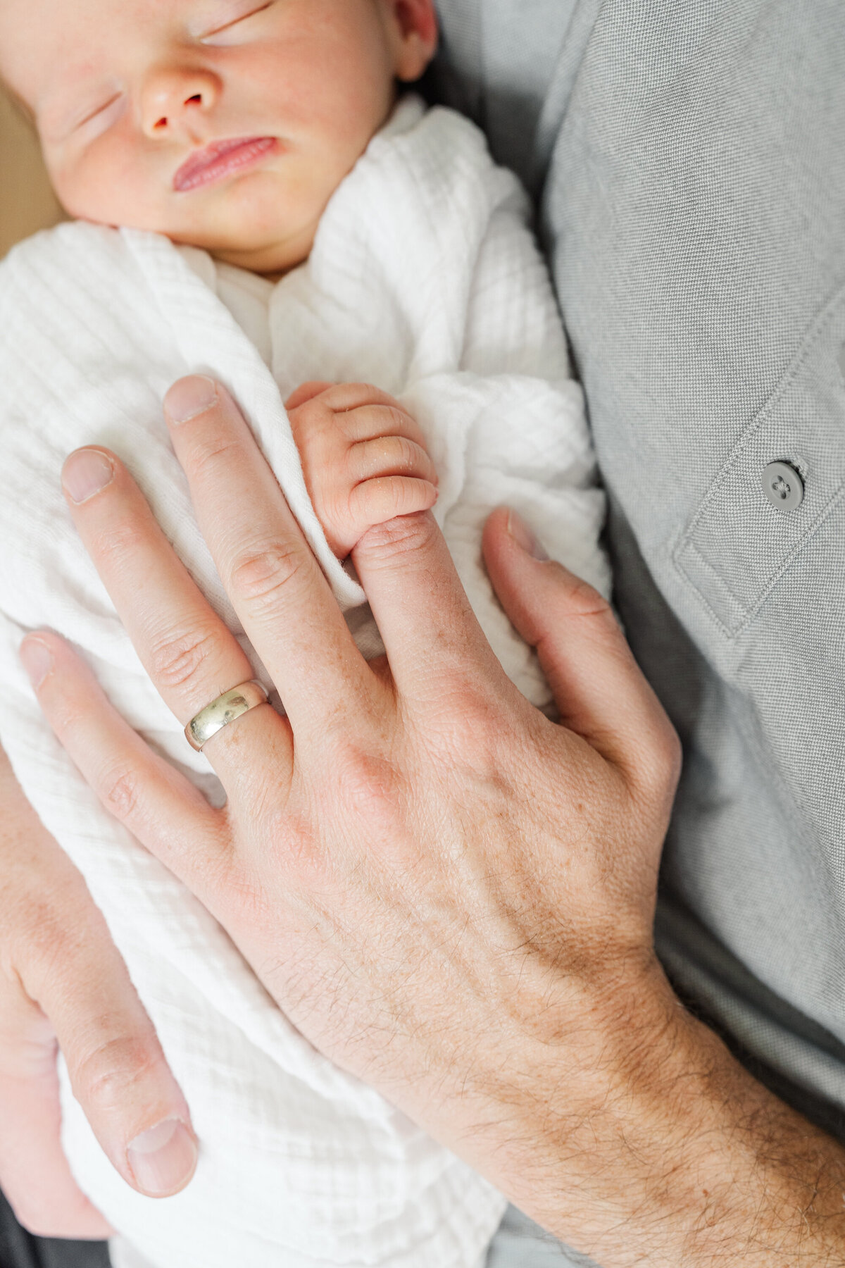 A father's hand gently resting on his newborn baby, offering a comforting and protective touch