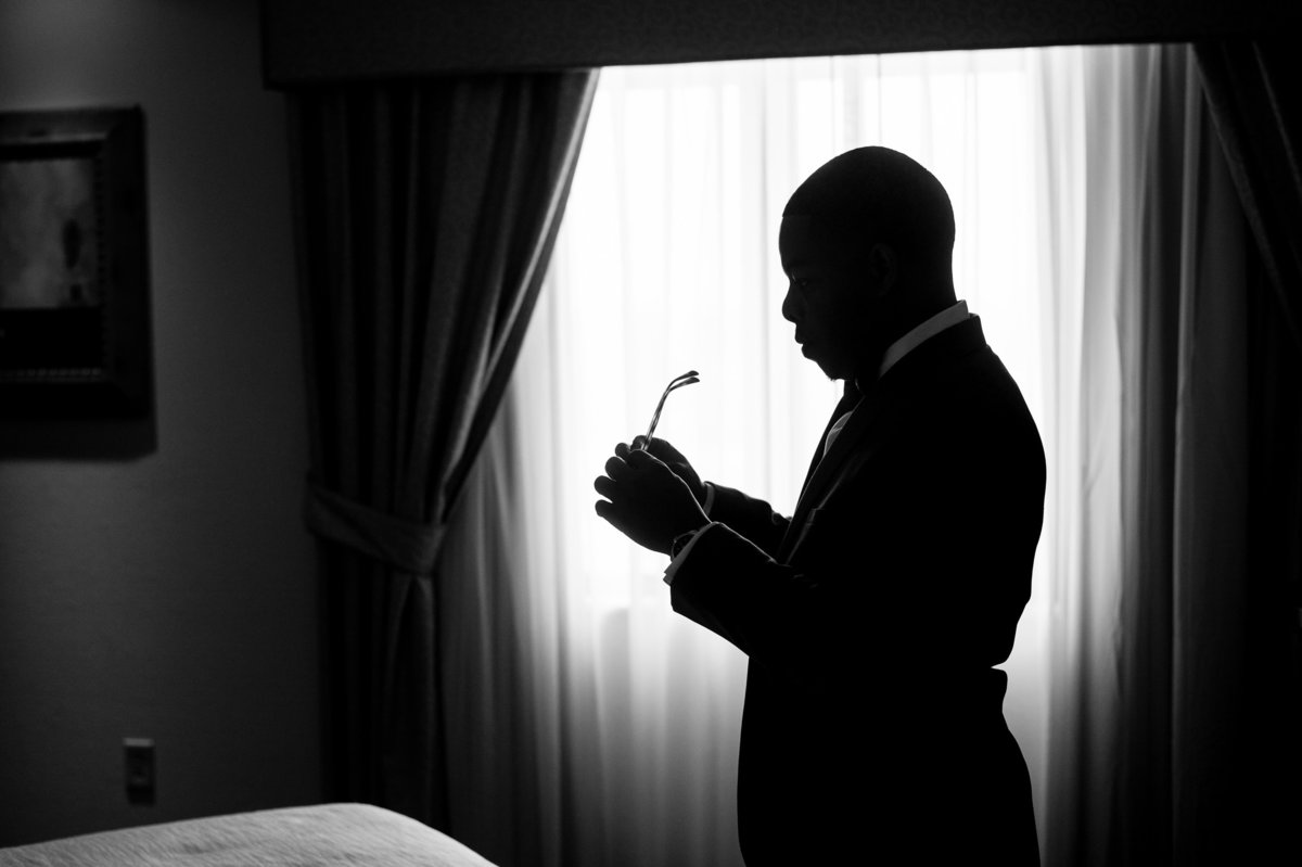 Black and white silhouette of groom getting ready at St Louis hotel.