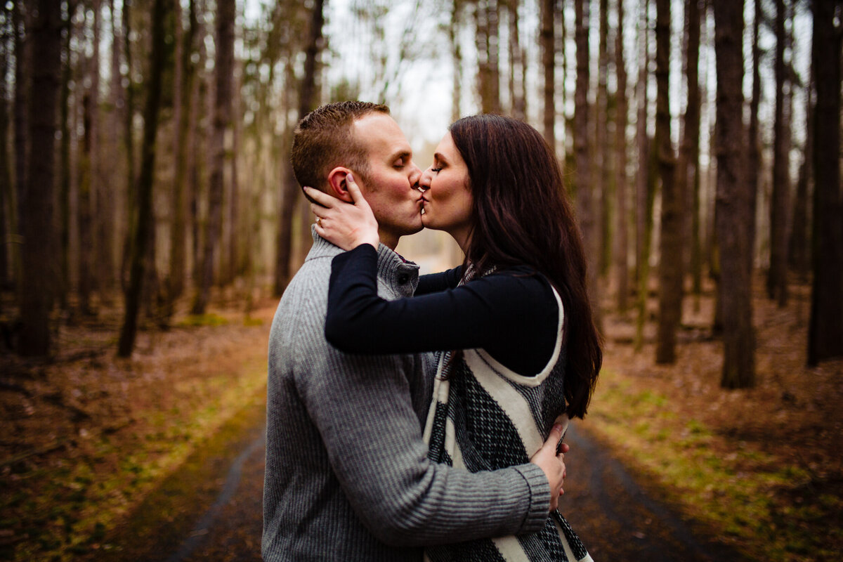 A couple has a quick kiss at Oak Openings Metropark during their engagement photos.  Photo By Adore Wedding Photography. Toledo Wedding Photographers