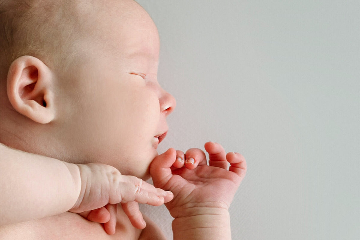 A newborn baby profile in close up on a white background.