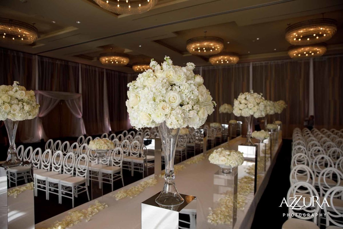 wedding ceremony with tall white flowers on mirrored pedestals and white chairs at Four Seasons Seattle