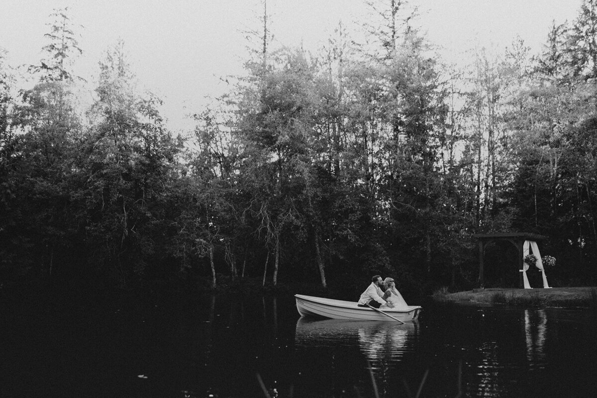 black and white image bride and groom kissing in canoe
