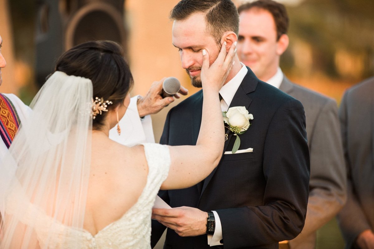 Bride wipes a tear away from her Groom's cheek as he reads his vows to her
