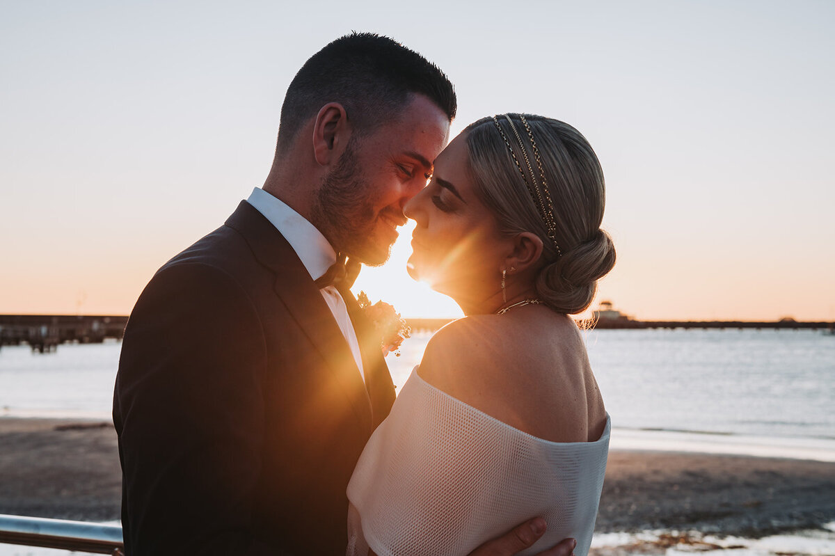 Bride and groom on St Kilda beach at sunset